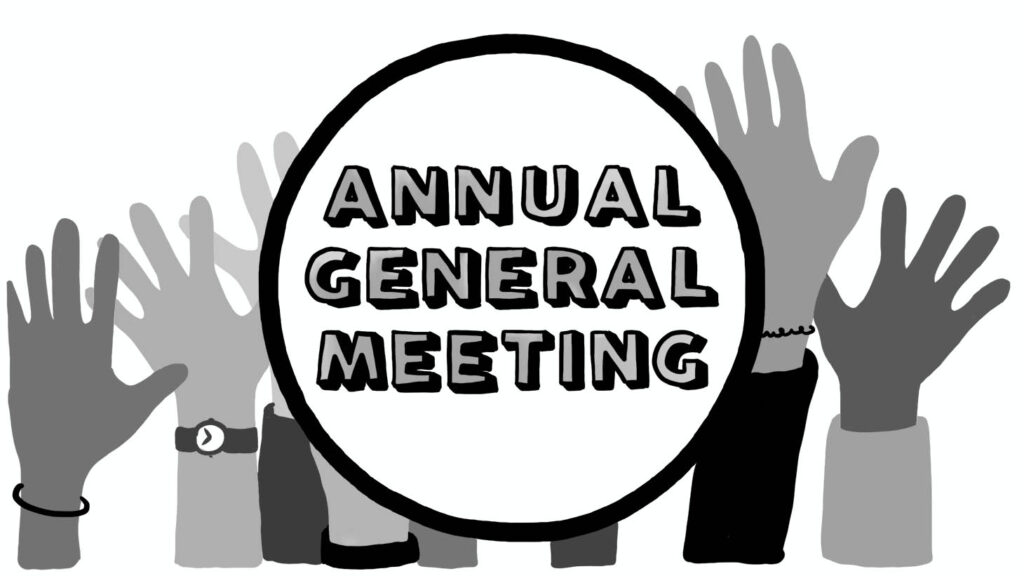 Annual General Meeting sign silhouetted by raised hands